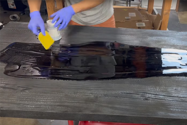 pouring epoxy resin onto the burned table top